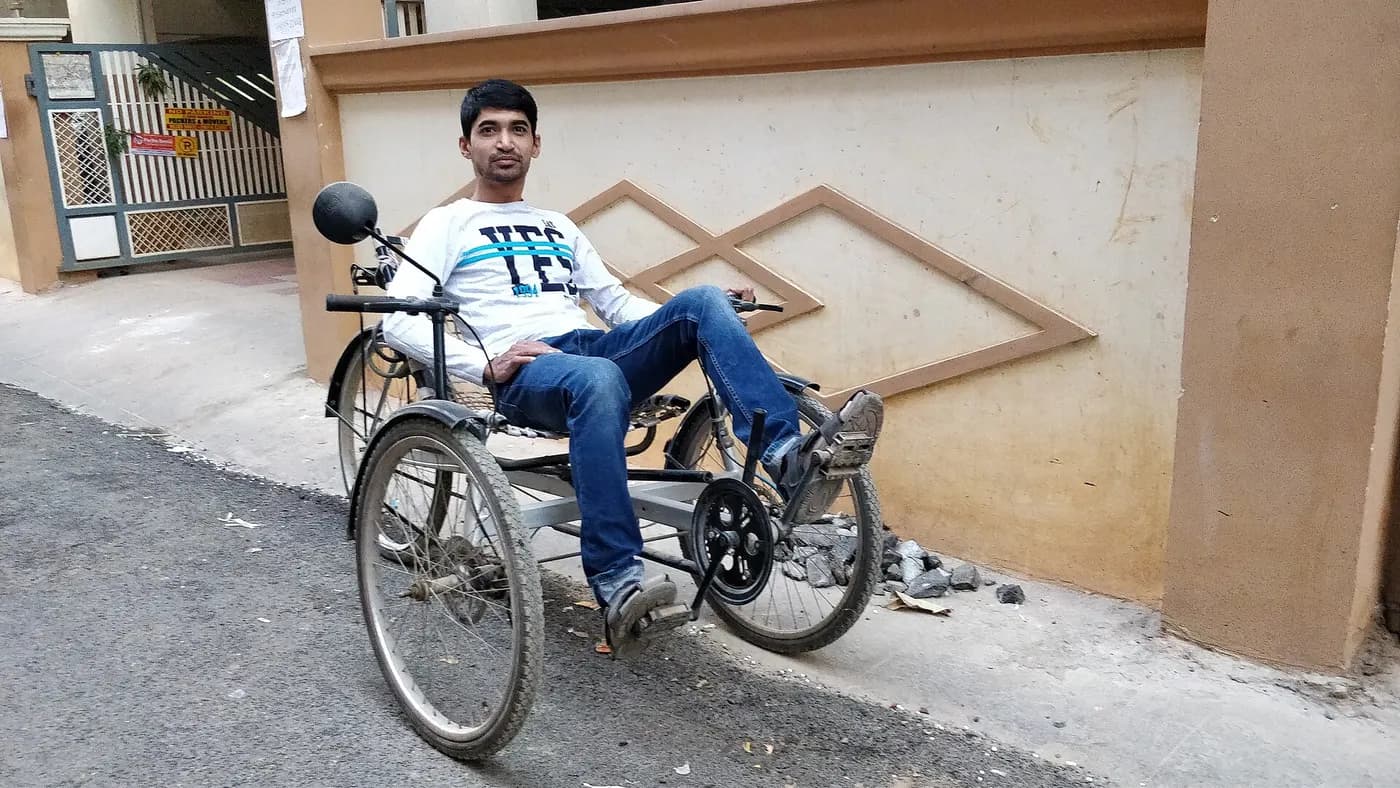 A rider seated on a recumbent tricycle with pedals ahead of the body.