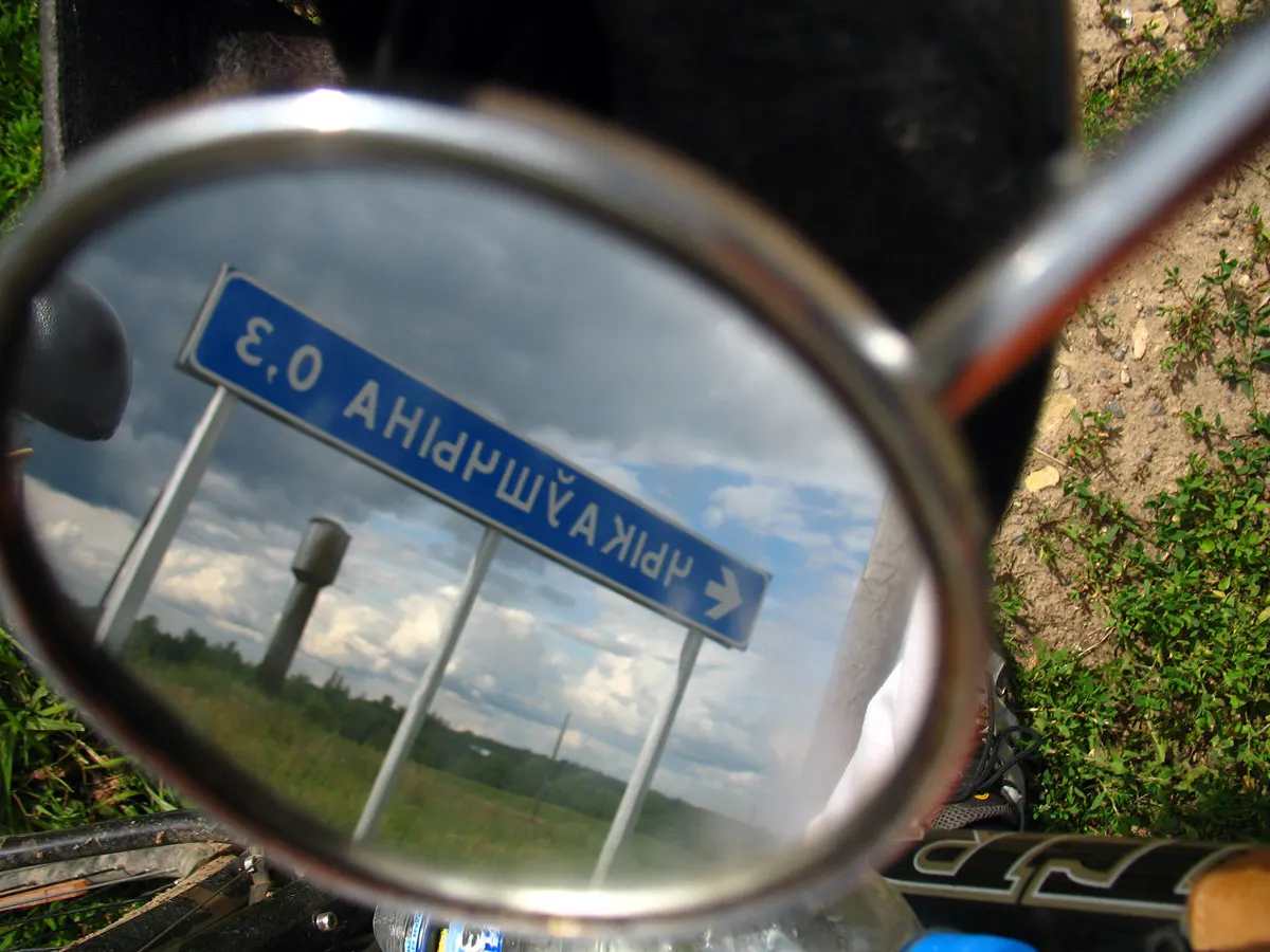 Roadside scene reflected in a bicycle handlebar mirror