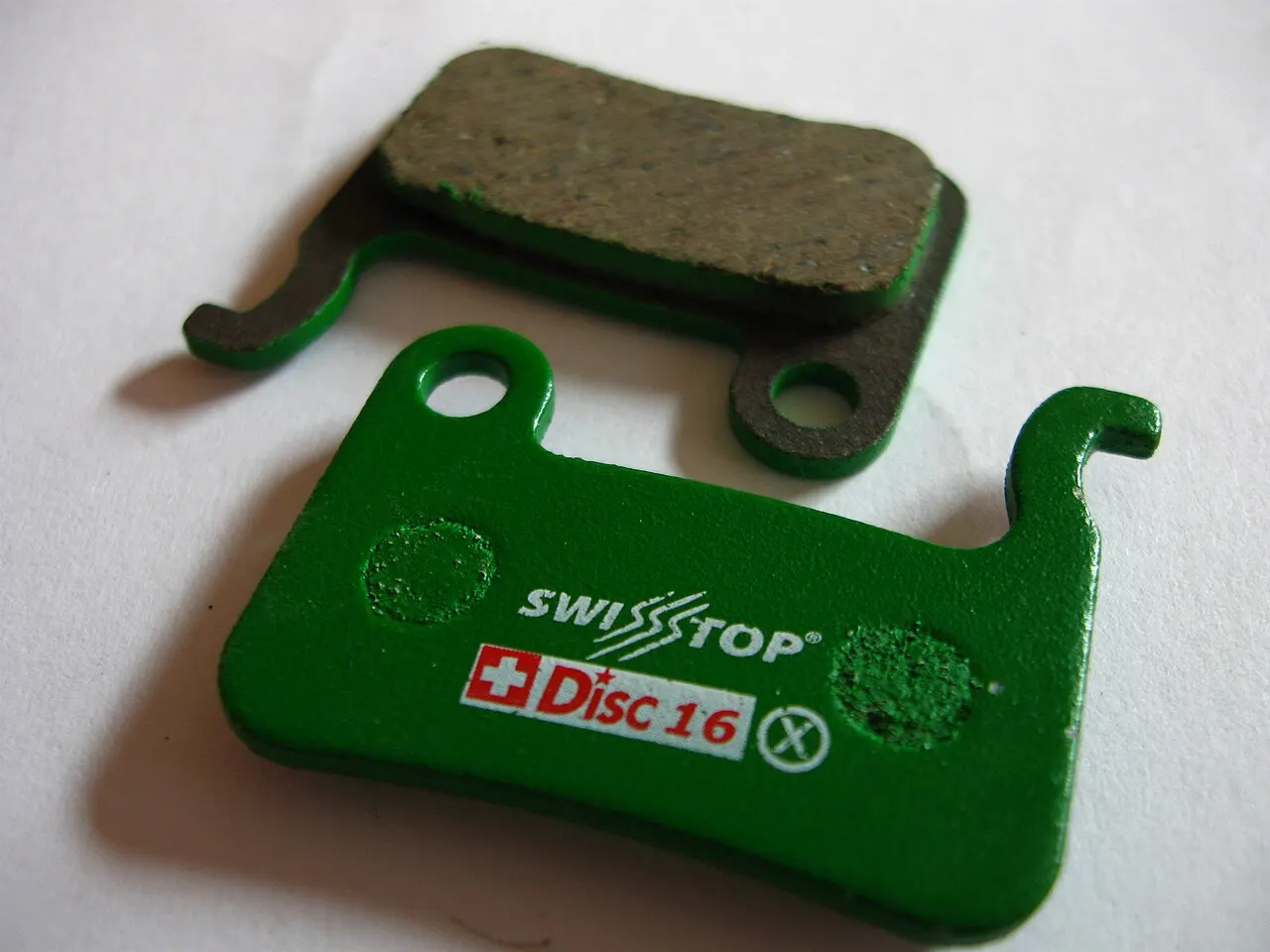 Two bicycle disc brake pads showing friction material and backing plate