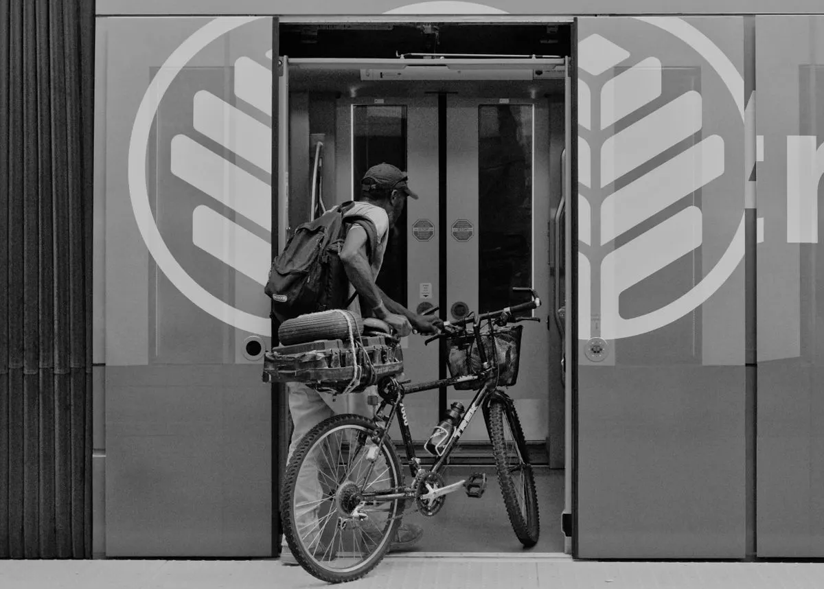 A cyclist with a backpack and bicycle entering a modern train station in an urban setting.