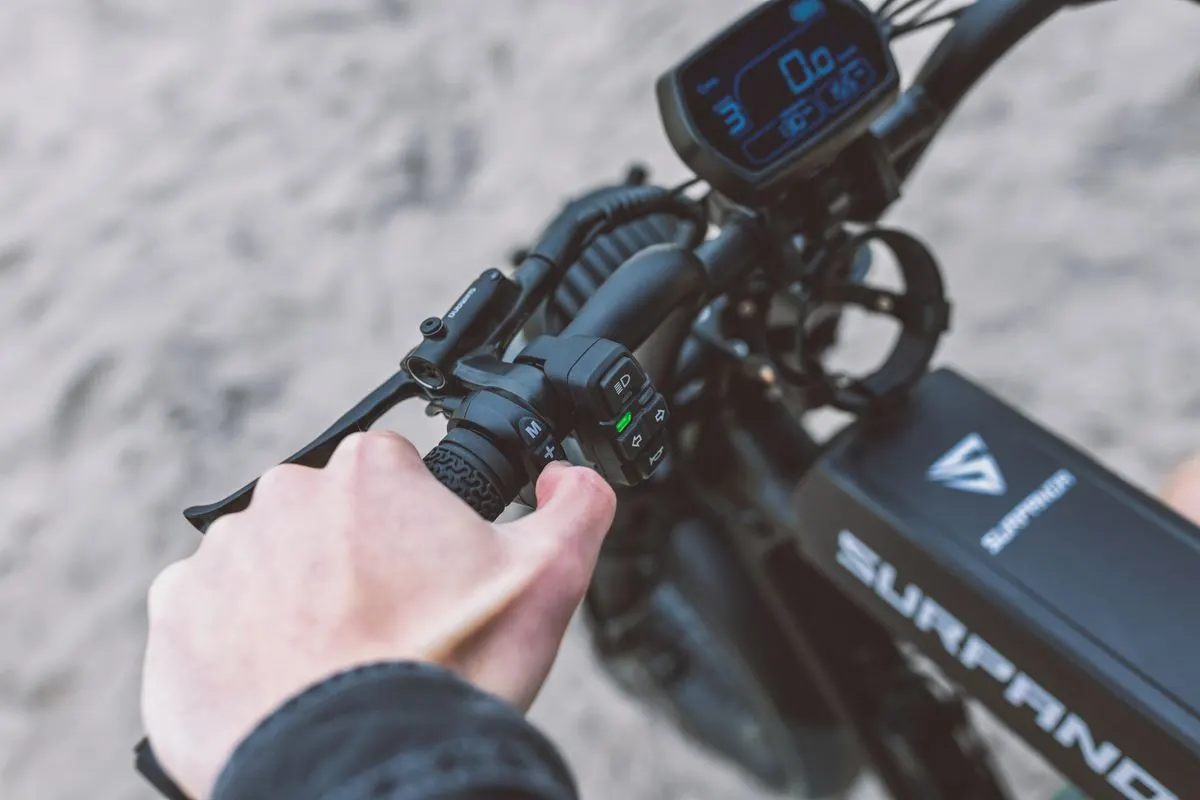 A person adjusting the handlebar controls of an electric bike, showcasing modern cycling technology.