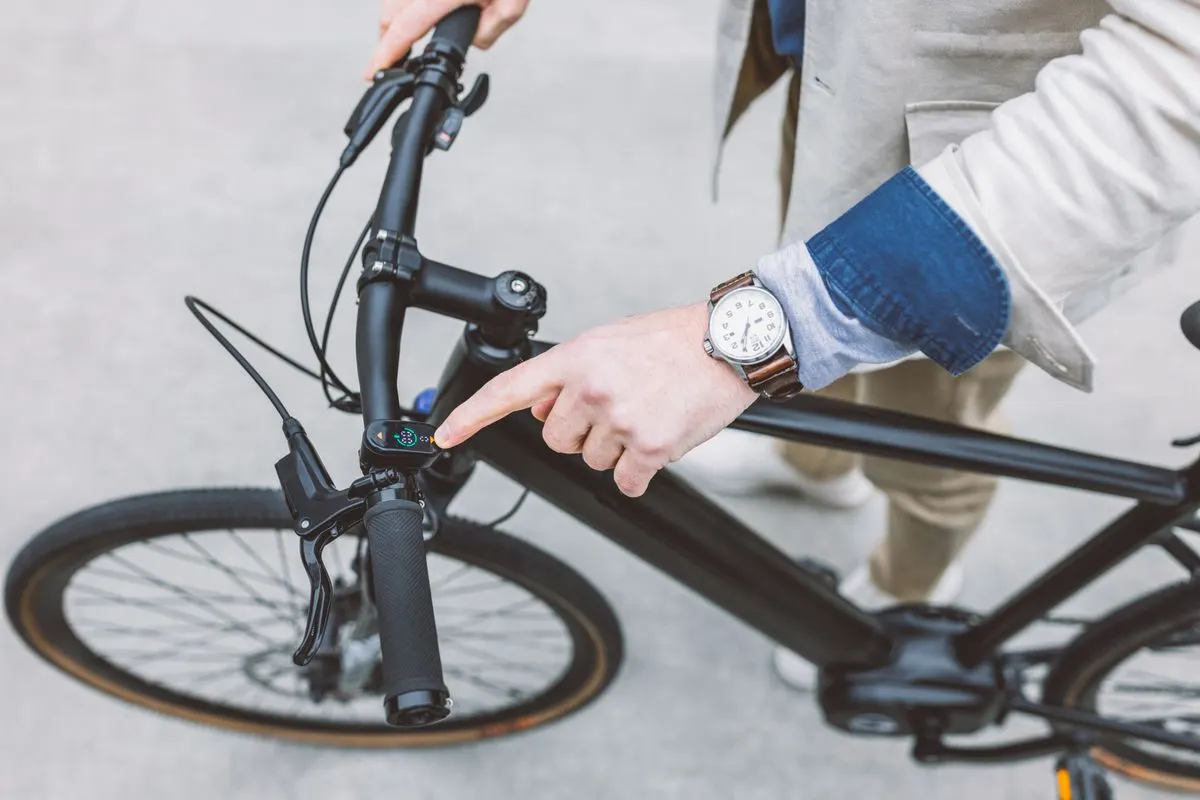 Rider operating a control beside an electric bicycle display