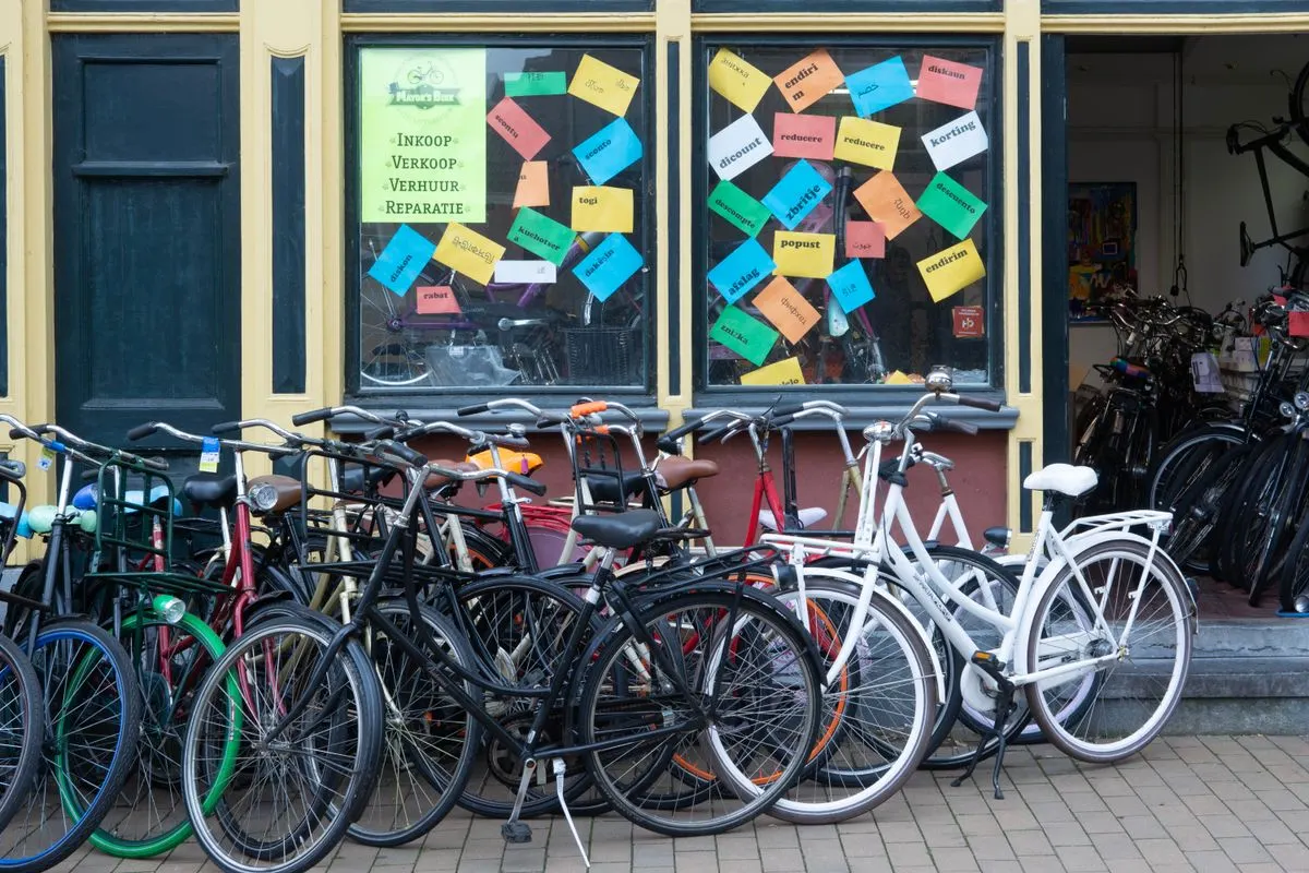 A bicycle shop exterior with various bikes and a colorful window display in an urban setting.