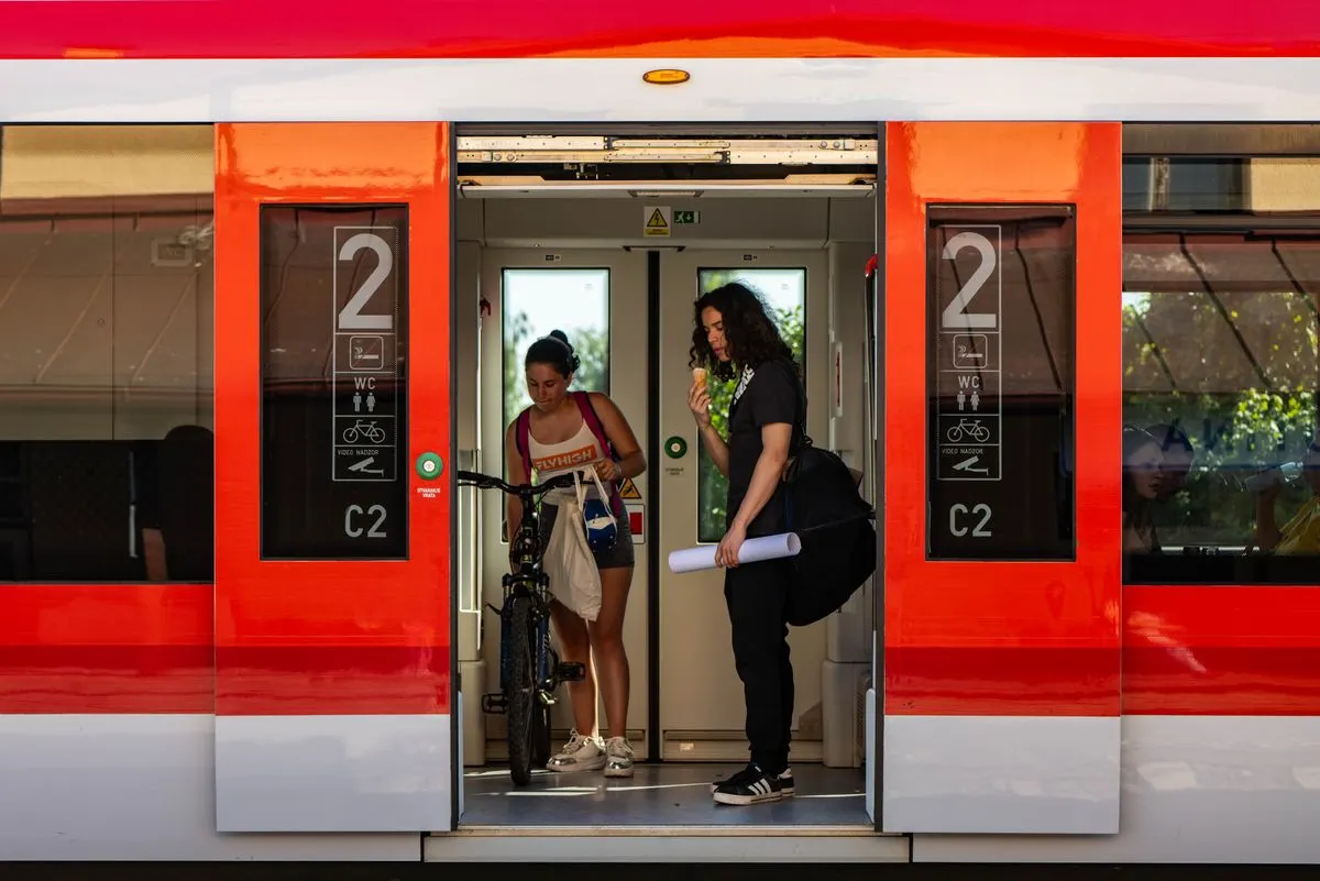 Two people with a bicycle stand at a train door, one eating ice cream.