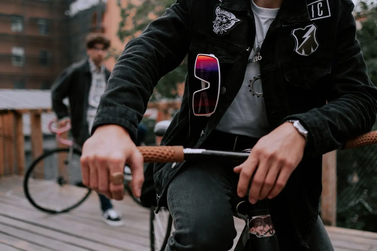 Trendy biker in urban setting with sunglasses and jacket, showcasing street fashion.