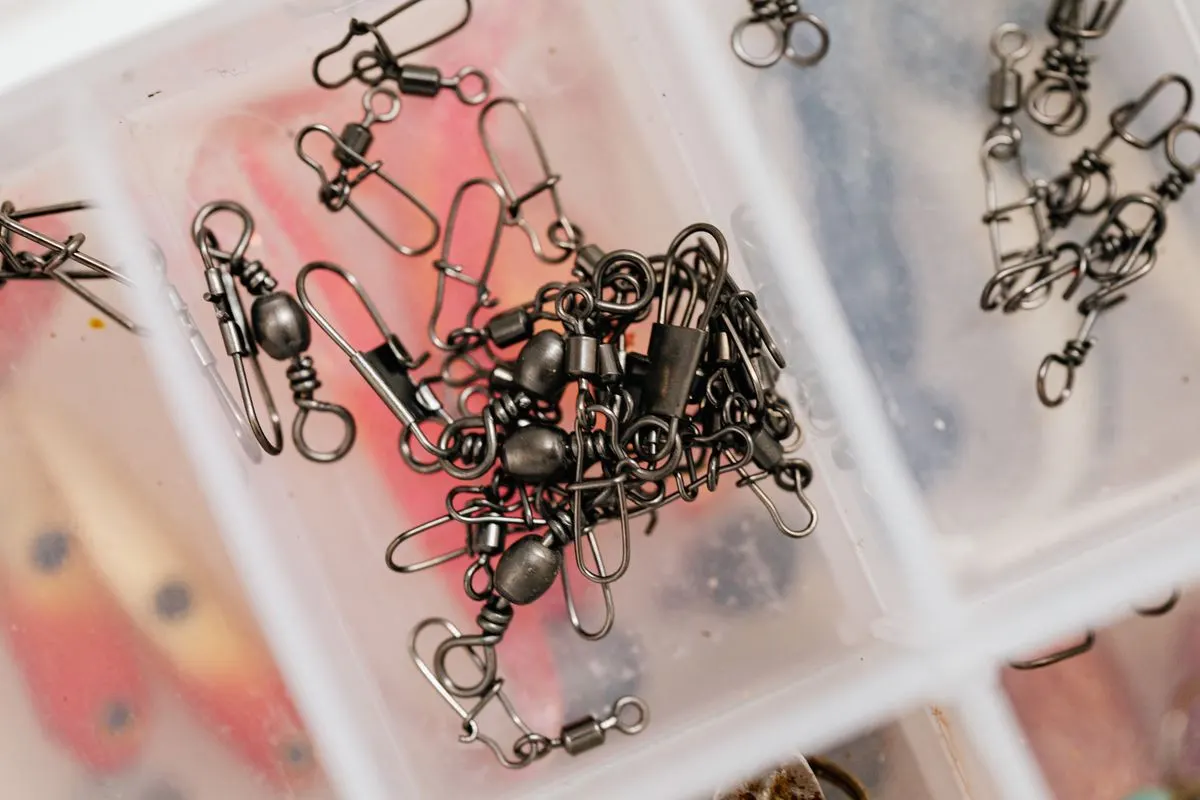 Detailed view of fishing swivels stored neatly in a clear plastic box.